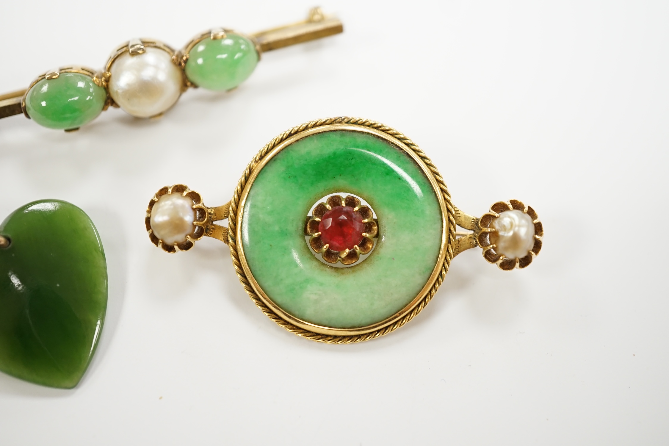 A Chinese 18k mounted, jade, cultured pearl and gem set disc brooch, 48mm, together with a yellow metal, jade and cultured pearl set bar brooch and a nephrite pendant.